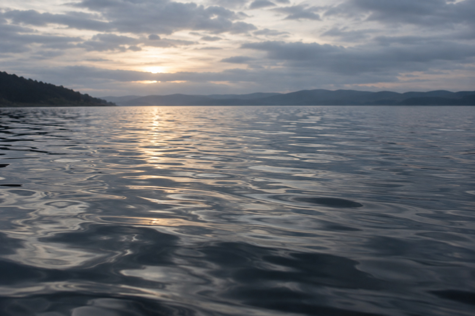 Suprafață de lac cu reflexii naturale în tonuri de albastru și gri.